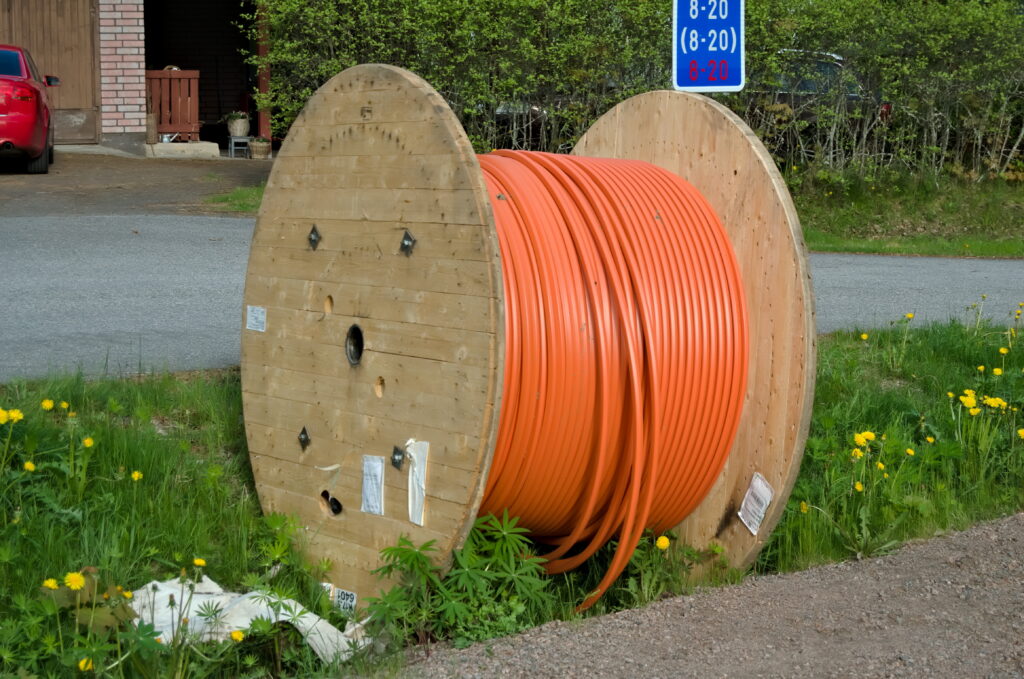Orange outdoor fiber optic cable on a wooden reel